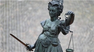 Eine Statue der Justitia hält eine Waage und ein Schwert in der Hand