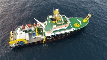 Forschungsschiff ATAIR des Bundesamts für Seeschifffahrt und Hydrographie (BSH) von oben auf offener See, mit grünem Helikopterdeck, gelbem Smiley und wissenschaftlicher Ausrüstung an Bord.