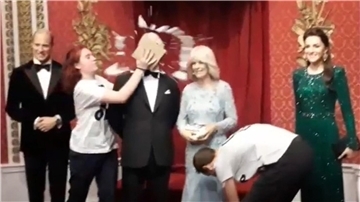 Das Wachsmodell von König Charles III. wird wird mit einem Kuchen beschmiert.