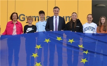 Europaabgeordneter David McAllister mit einer Schülergruppe und großer Europaflagge vor dem Gymnasium Langen