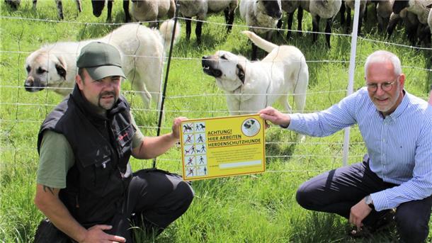 Deichschäfer René Krüger (links) und Thomas Ströer, Geschäftsführer Deichverband Osterstader Marsch, präsentieren im Mai 2022 die neuen Herdenschutzhunde mitsamt der dazugehörigen Warnschilder.