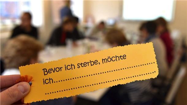 Ein sterbenskranker Patient in einem Hospiz hält einen Wunschzettel hoch. 