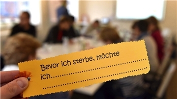 Ein sterbenskranker Patient in einem Hospiz hält einen Wunschzettel hoch. 