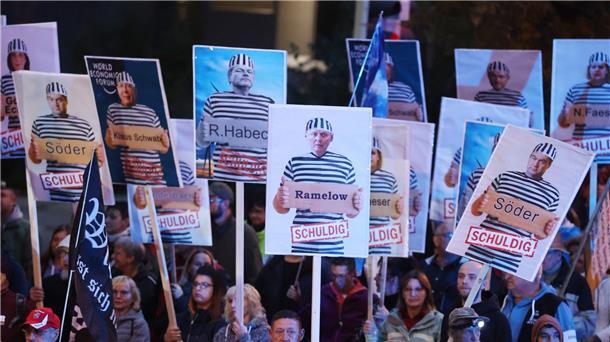 Demonstranten in Gera halten Plakate mit Politikern in Häftlingskleidung hoch.