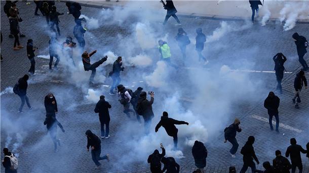 Rentenreform: Gewerkschaften wollen Frankreich lahmlegen Demonstranten treten während des Protestes in Paris Tränengaskanister weg.