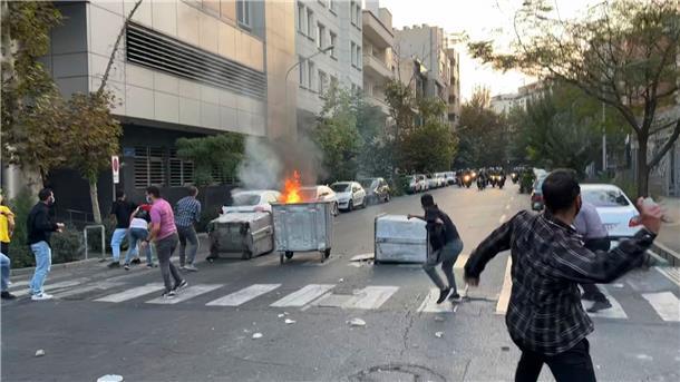 „Wir kämpfen, wir sterben“: Proteste und Unruhen im Iran Demonstranten werfen in Teheran während eines Protestes gegen den Tod von Mahsa Amini Steine auf Polizeieinheiten. Der Tod der 22-Jährigen hat landesweit Trauer und Empörung ausgelöst.