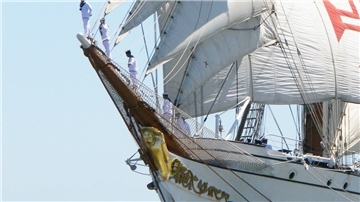 Eine Galionsfigur ist am Bug eines weißen Segelschiffes zu sehen. 