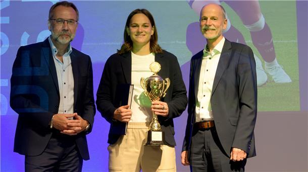 Eine junge Frau steht mit einem Pokal zwischen zwei Männern. Giovanna Hoffmann ist Bremerhavens "Sportlerin des Jahres 2024". 