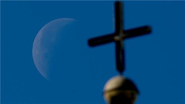 Familie trotz Kirchenasyl abgeschoben: Behrens erklärt Fall Der abnehmende Viertelmond ist hinter einem Kirchenkreuz zu sehen.