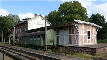 Bahnhofsgebäude mit altem Waggon und Gleis