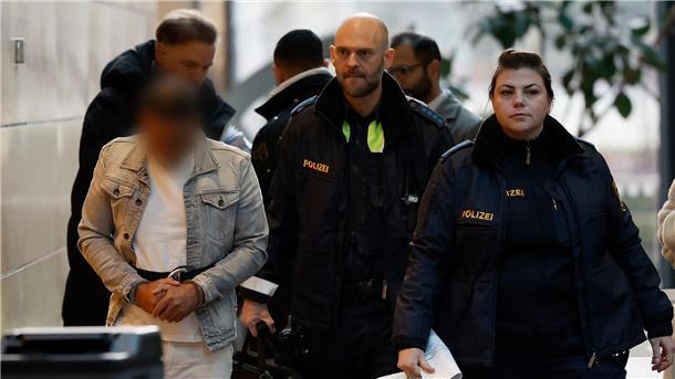 Mann gesteht Angriff auf vierfache Mutter Der Angeklagte (l) wird in Handschellen zum Sitzungssaal im Landgericht Würzburg gebracht.