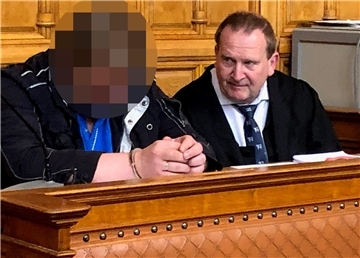 Zwi iMänner sitzen auf der Anklagebank in einem Gerichtssaal. 