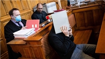 Der Angeklagte im Gerichtssaal. Hinter ihm sitzen seine beiden Anwälte.