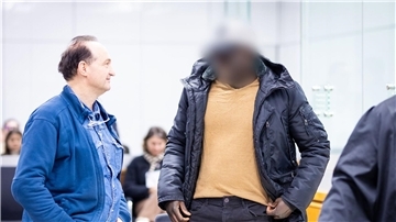 Der Angeklagte (r) steht im Gerichtssaal.