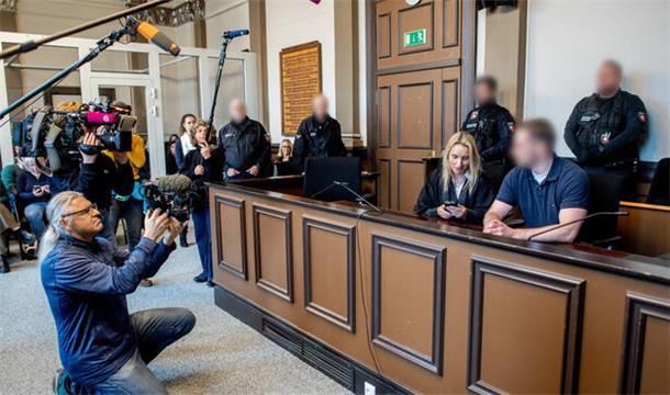 Der Angeklagte sitzt neben seiner Verteidigerin im Landgericht Verden und wird von Medienvertretern gefilmt.
