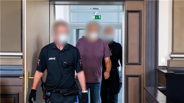 Ein wegen zweifachen Mordes und versuchten Mordes angeklagter Mann wird in einen Gerichtssaal des Landgerichts Verden geführt. 
