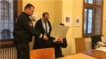 Der Angeklagte verdeckt vor Gericht sein Gesicht.