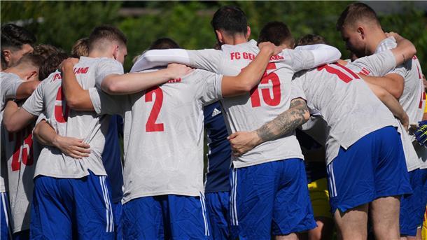 Fußballer stehen im Kreis und umarmen sich.