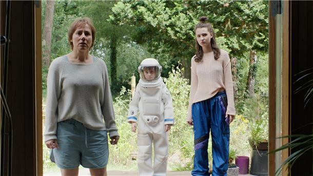 Zwei Frauen und ein kleiner Junge stehen in einer Tür. Der Junge ist als Astronaut verkleidet.