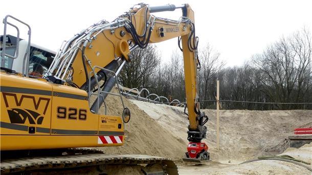 Der Bagger ist mit einer Rüttelplatte ausgestattet statt mit einer Schaufel, um den Sand zu verdichten.