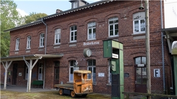 Bahnhofsgebäude mit Uhr und Karre