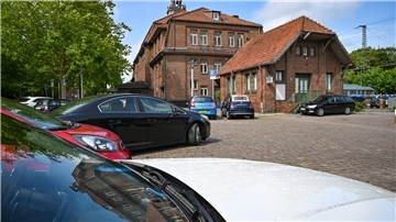 Parkende Autos vor dem Bahnhofsgebäude.