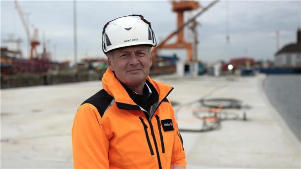 Heiko Obst steht auf dem schwimmenden Betonsegment in oranger Jack und Helm.