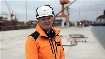 Heiko Obst steht auf dem schwimmenden Betonsegment in oranger Jack und Helm.