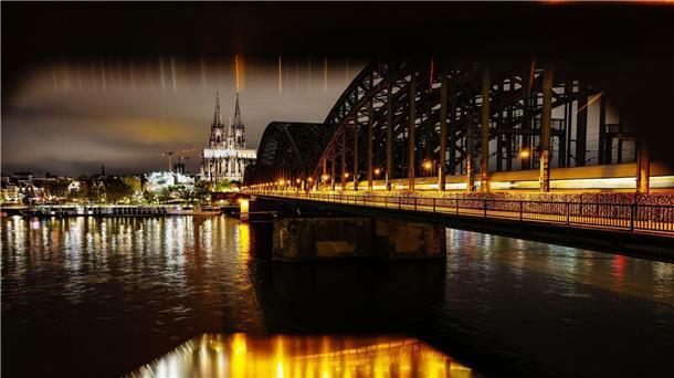 Der beleuchtete Kölner Dom und die Hohenzollernbrücke am frühen Morgen.