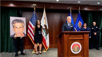 Der  Bezirksstaatsanwalt von Los Angeles, George Gascon, steht während einer Pressekonferenz neben dem Foto von Fernsehproduzent Eric Weinberg.