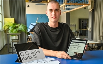Junger Mann zeigt etwas auf seinem ipad.