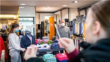 Der Bremerhavener Modegeschäftsinhaber Claus von der Heide und Mitarbeiterin Sandra Sappich kontrollieren einen Corona-Selbsttest einer Kundin vor dem Einkaufstermin.