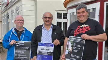 Männer stehen zusammen. Sie halten Plakate in den Händen. Dahinter ist das Centralkino Brake zu sehen. 