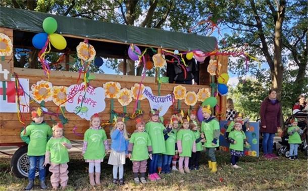Kinder stehen vor einem mit Luftballons geschmückten Wagen.