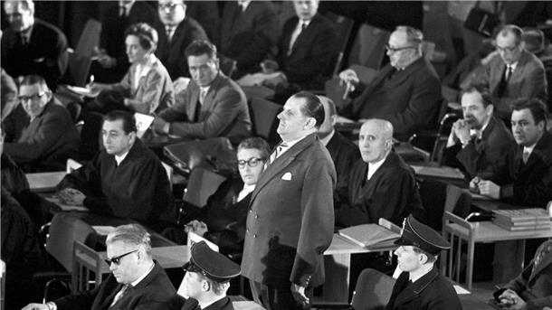 Als die Täter von Auschwitz in Frankfurt vor Gericht kamen Der erste Auschwitz-Prozess im Plenarsaal der Frankfurter Stadtverordnetenversammlung wird eröffnet. In der ersten Reihe sitzt der Angeklagte Victor Capesius (mit dunkler Brille), hinter ihm steht der Angeklagte Oswald Kaduk. (zu dpa: „Als die Täter von Auschwitz in Frankfurt vor Gericht kamen“)
