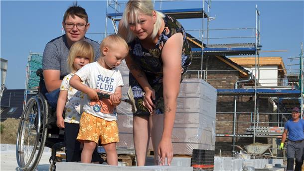Der erste Stein steht: Marvin und Yvonne Holst verlegen gemeinsam mit ihren Kindern Fiete und Lotta den ersten Stein ihres Traumhauses.