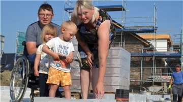 Der erste Stein steht: Marvin und Yvonne Holst verlegen gemeinsam mit ihren Kindern Fiete und Lotta den ersten Stein ihres Traumhauses.