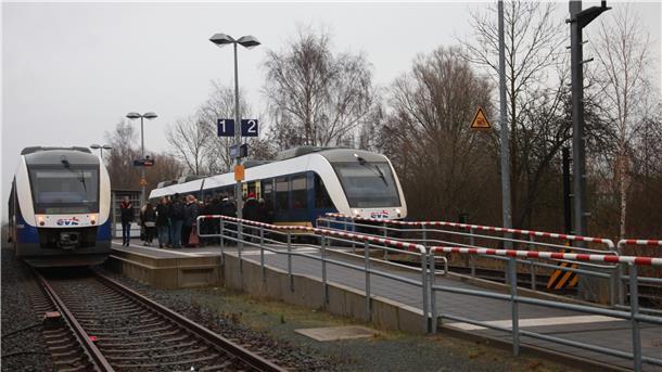 Zwei Züge auf Gleisen an einem Bahnhof.