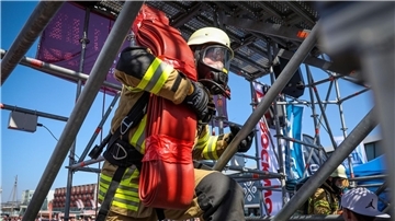 Der Feuerwehrmann Philipp Reumann von der Freiwilligen Feuerwehr Eckwarden steigt bei der „Firefighter Combat Challenge“ in Bremerhaven mit einem Schlauch auf einen Turm.
