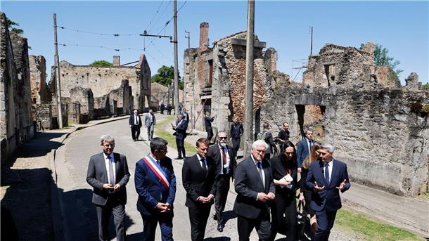 Der französische Präsident Emmanuel Macron und der deutsche Bundespräsident Frank-Walter Steinmeier gehen an Ruinen in Oradour-sur-Glane vorbei.