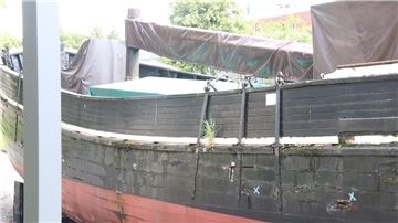 Ein altes Holzschiff, das an Land ausgestellt wird.