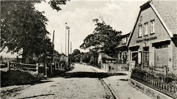 Kopfsteinpflasterstraße mit Geschäftshaus auf der rechten Seite