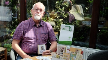 Ein Mann sitzt im Garten mit Briefmarken.
