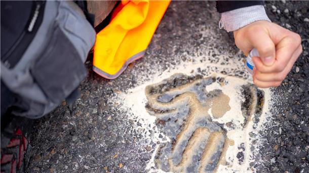 Klimaschützer-Gruppe will auf Klebeaktionen verzichten Der Handabdruck eines Aktivisten auf einer Straße.