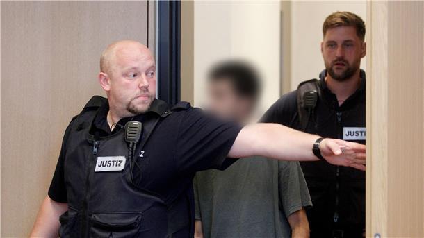 Der Hauptangeklagte wird von Justizbeamten in den Gerichtssaal geführt.