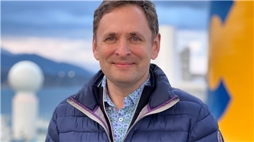 Ein Mann mit blauer Jacke und einem Hemd darunter.