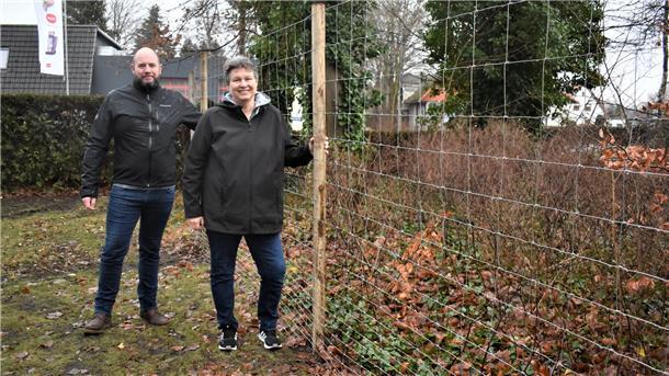 Der Kampf gegen die unerwünschten Rehe auf dem Langener Friedhof soll endlich ein Ende haben: Ortsbürgermeister Sascha Kuntzmann und Anja Heins von der Stadt Geestland freuen sich, dass der neue Wildzaun steht.