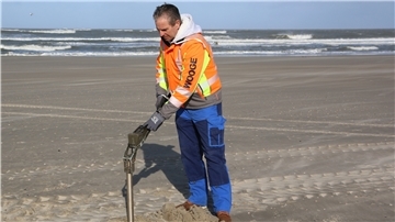 Der Kampfmittelräumer Hans Warfsmann steht auf dem Strand von Wangerooge und sucht mit Hilfe einer Sonde nach alter Munition.