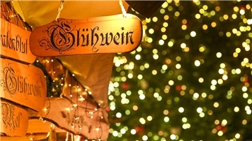 Ein Holzschild mit der Aufschrift „Glühwein“ hängt an einem Marktstand.