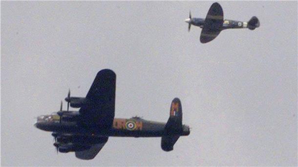 Ein Lancaster-Bomber wird von einem Jagdflugzeug begleitet.